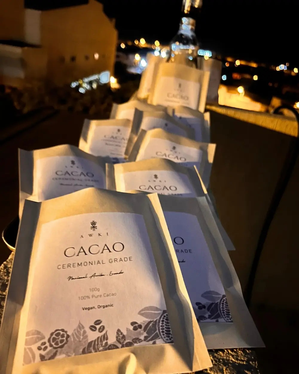 Multiple Awki Ceremonial Grade cacao pouches displayed at night with city lights in the background
