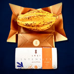AWKI Intensity chocolate bar with golden cacao fruit on copper gift envelope, showcasing premium Ecuadorian cacao presentation.