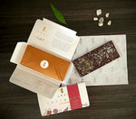 Unboxed Awki Intimacy chocolate bar with sparkling toppings and premium gold envelope packaging on dark wood surface