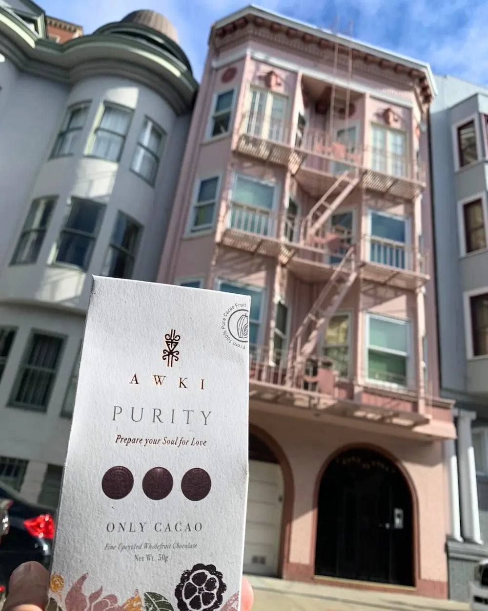 Awki Purity chocolate bar held in front of a classic Victorian-style building in San Francisco